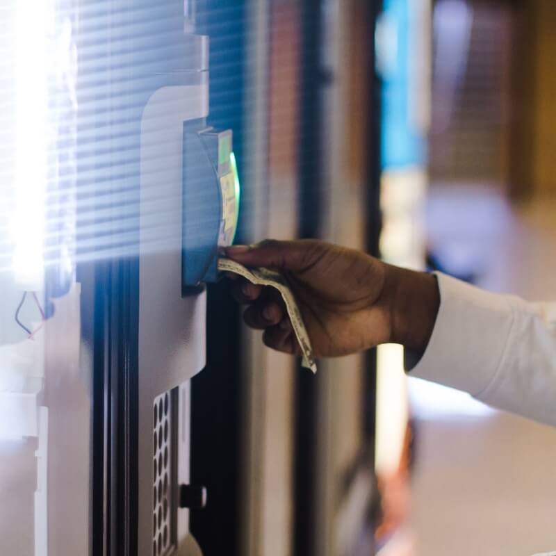 A person inserts a banknote into the payment terminal of a vending machine.
