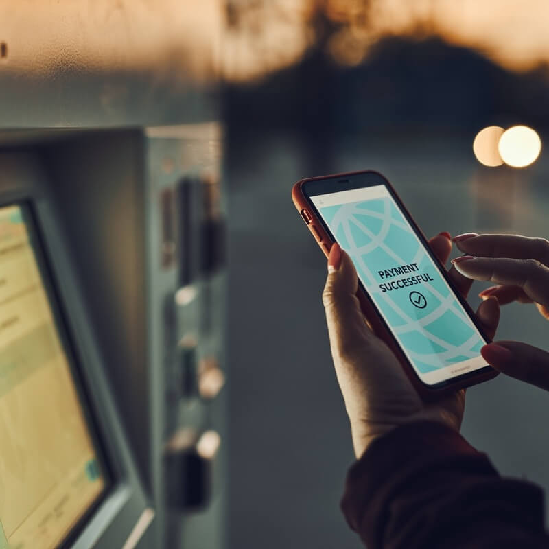 A woman holds a smartphone where it reads "payment successful".