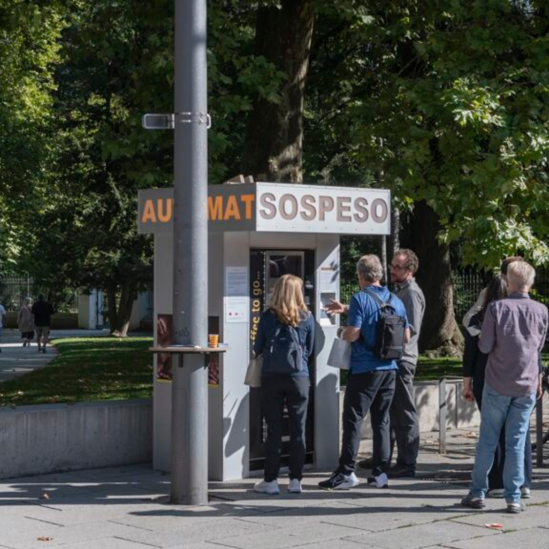 In front of the Automat Sospeso installation, a line of people wait to make a purchase.